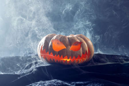 Composition of halloween carved pumpkin with smoke on black background. Halloween tradition and celebration concept.の写真素材