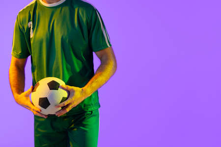 Caucasian male soccer player with football over neon pink lighting. Sport, movement, training and active lifestyle concept.の写真素材