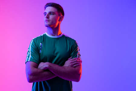 Caucasian male soccer player with arms crossed over neon pink lighting. Sport, movement, training and active lifestyle concept.の写真素材