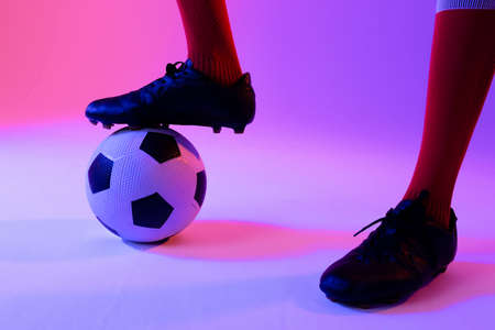 Male soccer player with football over neon pink lighting. Sport, movement, training and active lifestyle concept.の写真素材