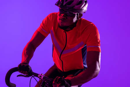 African american male cyclist with bicycle over neon pink lighting. Sport, movement, training and active lifestyle concept.の写真素材