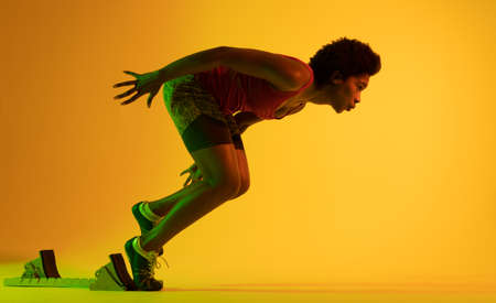 Image of african american female athlete preparing for run in yellow lighting. Sport, movement,...