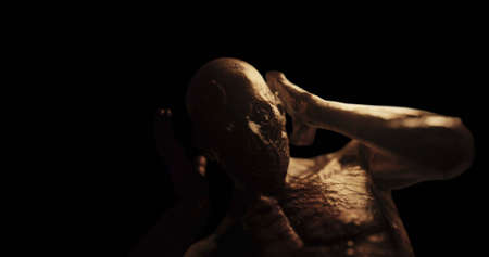 Image of distressed shirtless bald figure holding head in pain in dark room. Fear, horror and...
