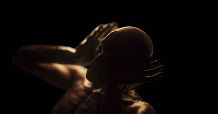 Image of distressed shirtless bald figure holding head in pain in dark room. Fear, horror and suffering concept digitally generated image.の写真素材