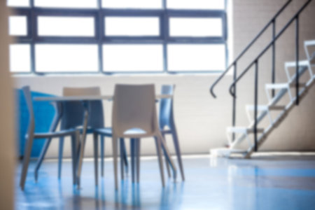 Empty table and chairs against windows by steps in building