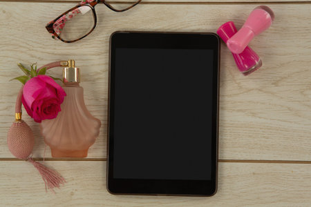 Digital tablet, perfume, flower, and spectacle on wooden table, Close-upの写真素材