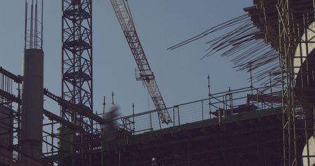 Building and crane at construction site against sky
