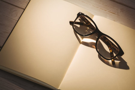Directly above shot of book with eyeglasses on table