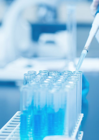 Scientist dropping the reagent into test tube for reaction testing in chemical laboratory