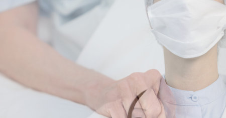 Digital illustration of a doctor wearing a face mask over a person tightening his fist in the background. Medicine public health pandemic coronavirus Covid 19 outbreak concept digital composite.の写真素材