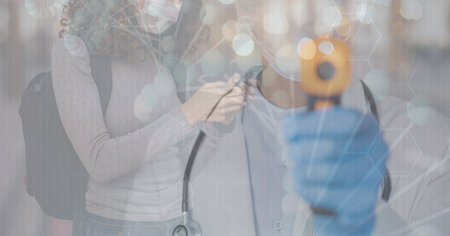 Digital illustration of a doctor wearing a face mask and protective gloves, using an electronic thermometer over a woman wearing a face mask, using a smartphone, walking on a street in the background. Medicine public health pandemic coronavirus Covid 19 outbreak concept digital composite.の写真素材