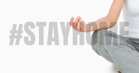 The words #StayHome with a Caucasian woman meditating. Public health pandemic coronavirus Covid 19 social distancing and self isolation in quarantine lockdown conceptの写真素材
