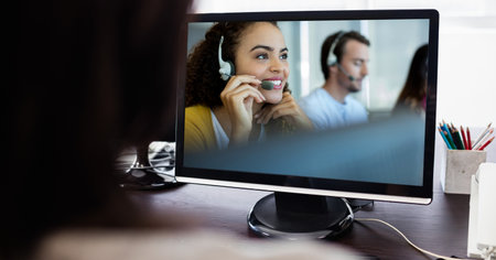 Woman using a computer with group of multi ethnic coworkers in their offices, having a video meeting...