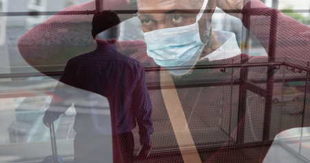 Digital illustration of a man putting on a face mask over a man standing in an airport, carrying a...