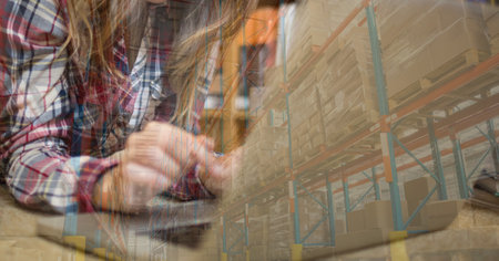Mid section of a Caucasian woman using laptop computer at home shopping on line over warehouse with...