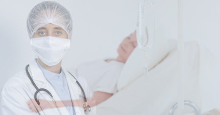 Digital illustration of a doctor wearing a face mask, looking at the camera over a senior patient lying in a hospital bed in the background. Medicine public health pandemic coronavirus Covid 19 outbreak concept digital composite.の写真素材