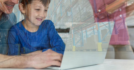 Happy Caucasian man with his son using laptop computer at home shopping on line over warehouse with shelves full of cardboard parcel boxes in the background. Online shopping ecommerce social distancing and self isolation in quarantine lockdown concept digital composite.の写真素材
