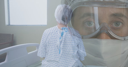 Digital illustration of a senior female patient sitting on a hospital bed over a senior woman wearing face mask and protective goggles in the background. Medicine public health pandemic coronavirus Covid 19 outbreak concept digital composite.の写真素材