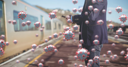 Digital illustration of macro Covid-19 cells floating over a man standing on a train station, using a smartphone. Coronavirus Covid-19 pandemic concept digitally generatedの写真素材