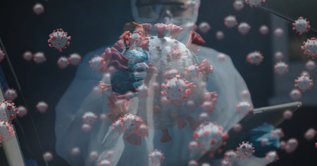 Digital illustration of macro Covid-19 cells floating over male Caucasian scientist wearing protective clothes using a digital tablet. Coronavirus Covid-19 pandemic concept digital compositeの写真素材