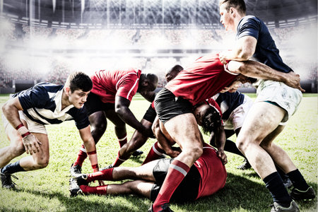Two teams of multi-ethnic rugby players playing rugby at a sports stadium, wearing team strip, facing each other, one player ling on grass. Sport and competition concept digital composite.の写真素材