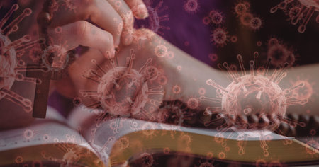 Digital illustration of macro Covid-19 cells floating over Caucasian hands praying over Bible with a rosary. Religious faith in time of coronavirus global pandemic concept, digital composite.の写真素材