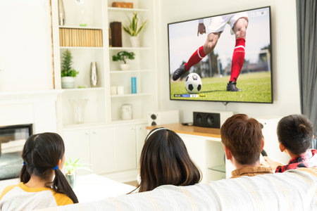 Diverse children watching tv with football match on screen. Global sport concept, digital composite image.の写真素材