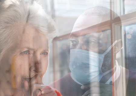 Worried senior Caucasian senior woman looking ahead and mixed race man wearing a face mask...