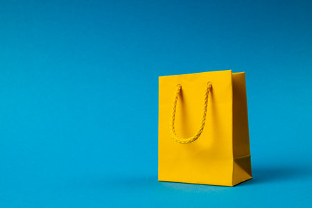 Composition of yellow paper shopping bag on blue background. Retail, shopping and black friday concept.の写真素材