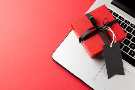 Composition of laptop with gift tag and present on pink background. Retail, shopping and black friday concept.の写真素材