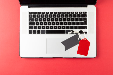 Composition of laptop and gift tags on pink background. Retail, shopping and black friday concept.の写真素材