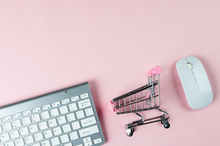 Composition of keyboard, mouse and shopping cart on white background. Retail, shopping and black friday concept.の写真素材