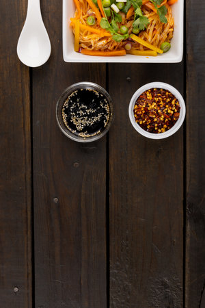 Overhead view of asian wok stir fry noodles and chopsticks, spoon and condiments on wood. Asian tasty home cooked food and healthy eating.の写真素材