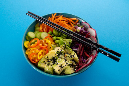 Overhead view of hawaiian poke bowl with chopsticks on blue background. Hawaiian tasty fresh food and healthy eating.の写真素材