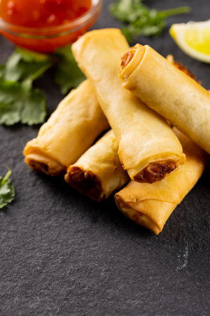 Close up of asian spring rolls, sliced lime and chilli sauce on grey background. Asian tasty home cooked food and healthy eating.の写真素材