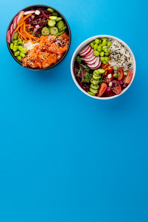 Overhead view of two hawaiian poke bowls with copy space on blue background. Hawaiian tasty fresh...