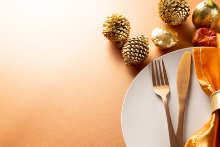 Overhead view of plate and cutlery with autumn decoration and copy space on orange background. Thanksgiving, autumn, fall, american tradition and celebration concept.の写真素材