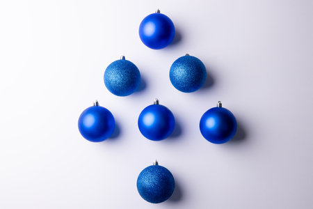Image of christmas decoration blue baubles forming christmas tree copy space on white background. Christmas, tradition and celebration concept.の写真素材