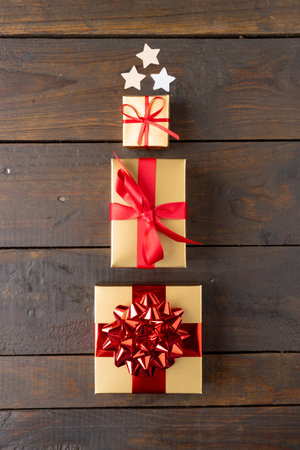 Image of christmas gifts and stars forming christmas tree and copy space on wooden background....