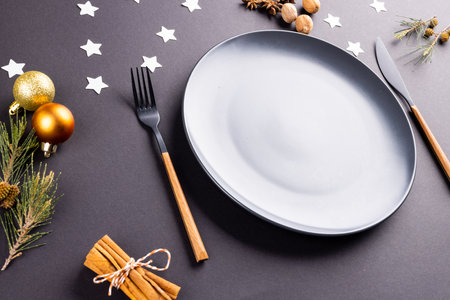Image of christmas place setting with plate and cutlery on black background. Christmas, tradition...