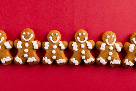 Image of row of christmas gingerbread man biscuits with copy space on red. Christmas, tradition and celebration concept.の写真素材