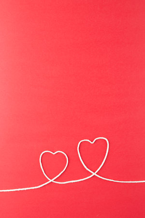 Vertical image of hearts made of white string on red surface. Clothes, textiles, fashion, style and...
