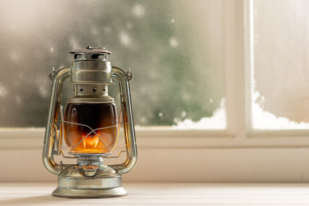 Vintage christmas shining oil lantern over frozen and snowy window. Christmas, tradition and celebration concept.の写真素材