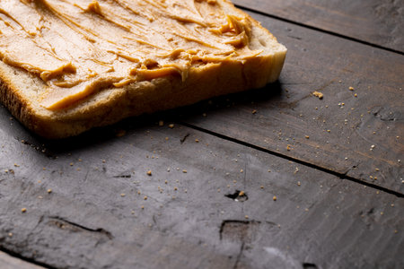 Image of bread slice with peanut butter on wooden surface. Food, breakfast, nutrition and american...