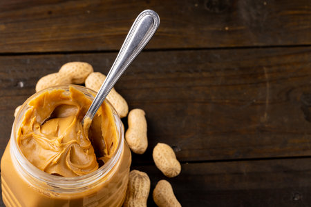 Image of jar with peanut butter and nuts on wooden surface. Food, breakfast, nutrition and american cuisine concept.の写真素材