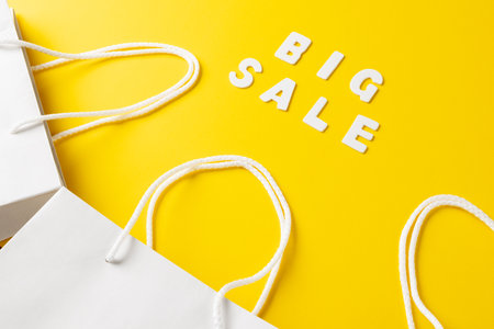 Composition of paper bags and big sale text on yellow background. Retail, shopping and black friday concept.の写真素材