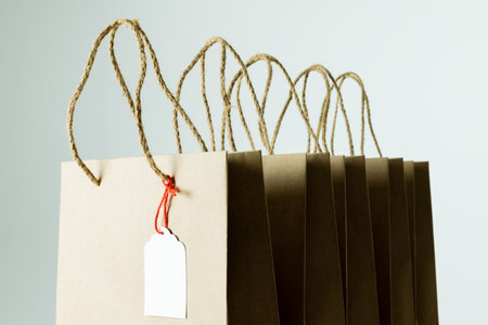 Composition of gift tag and paper shopping bags on white background. Retail, shopping and black friday concept.の写真素材