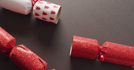 Image of red and white christmas crackers on grey background. Christmas, tradition and celebration concept.の写真素材