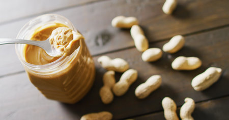 Image of close up of peanut butter and peanuts on wooden background. Food, party and copy space...