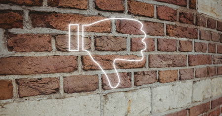 Composite of illuminated digital dislike button icon against brick wall, copy space. Thumbs down, social media, negative emotion, hand, symbol and feedback concept.の写真素材